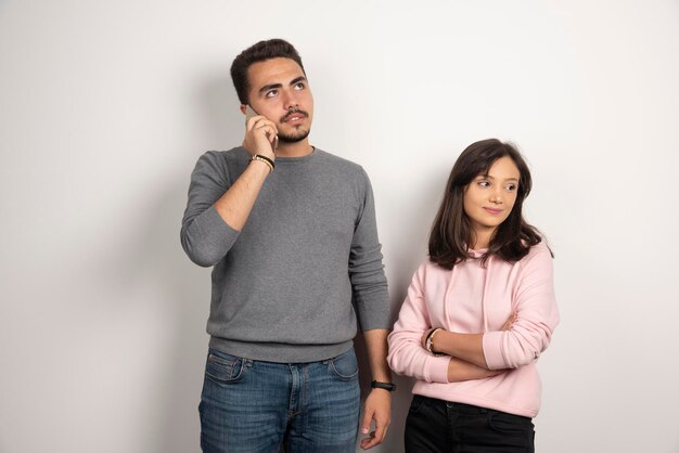 Woman standing while man talking with telephone.