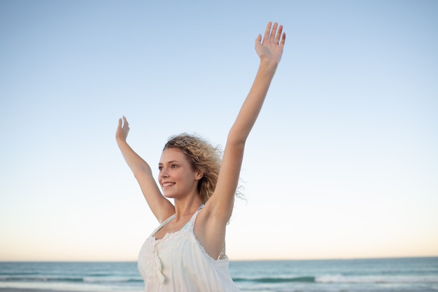 Женщина с поднятыми руками на пляже