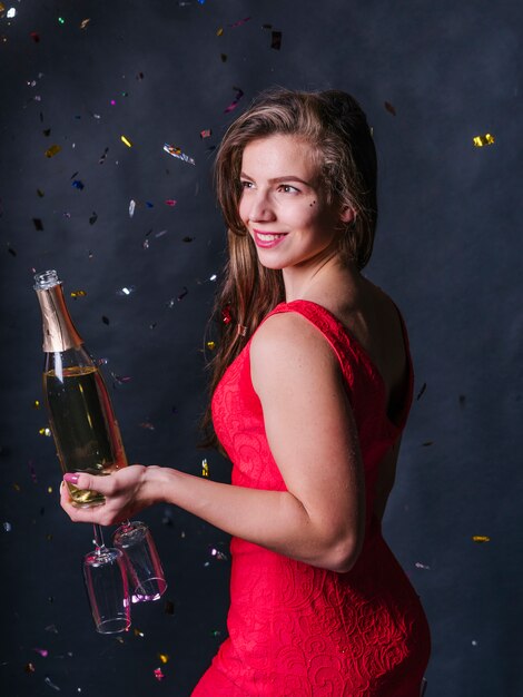 Женщина, стоящая с бутылкой шампанского и очки