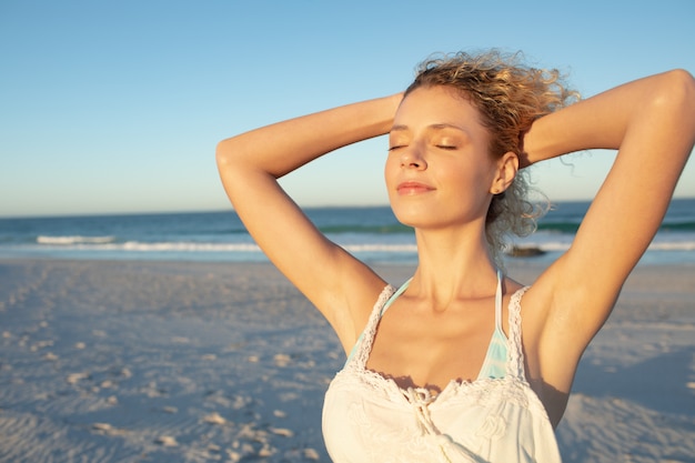 Woman standing with eyes closed on the beach