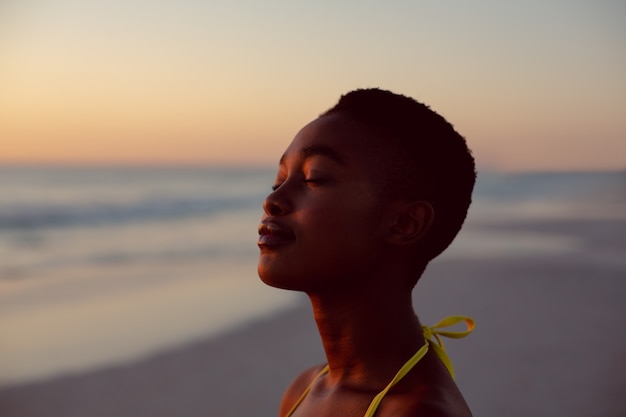 Free photo woman standing with eyes closed on the beach