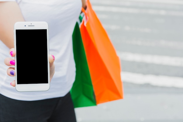 Woman standing with phone and shopping bags 