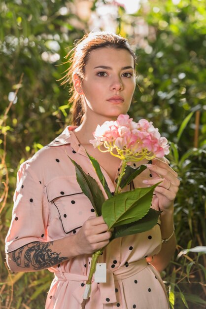 Woman standing with pink flower in hand