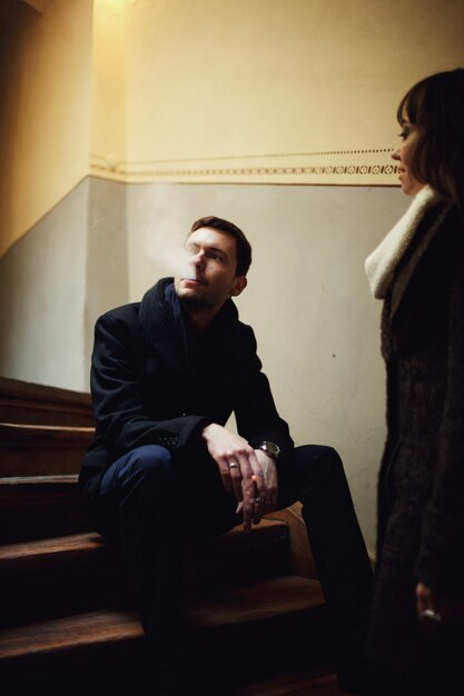 Женщина стоит возле человека, который сидит на лестнице