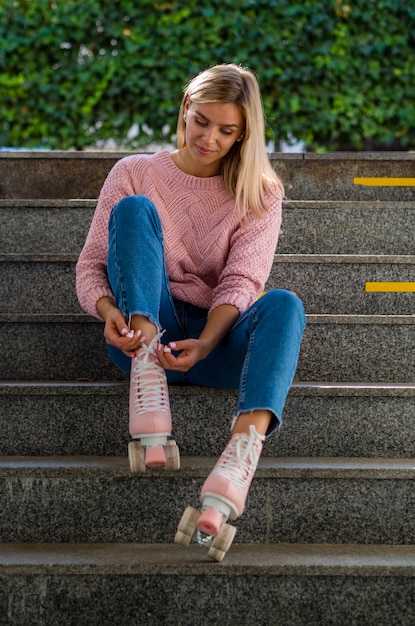 Free photo woman on stars tying shoelace on roller skates