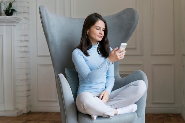 Foto gratuita donna che sta nel suo letto mentre fa una videochiamata sul suo smartphone