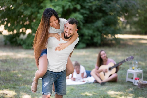 Free photo woman staying on man's back outside