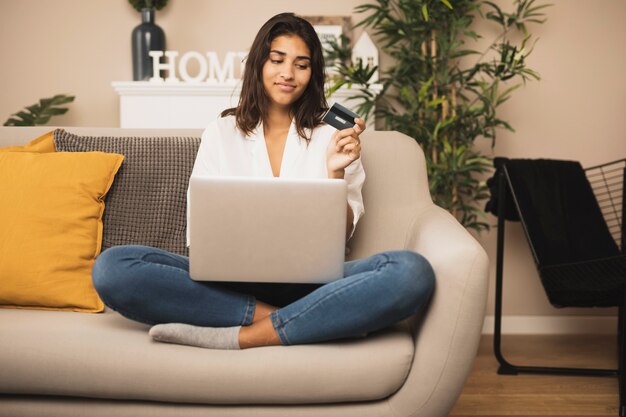 Woman staying on sofa and holding a credit card