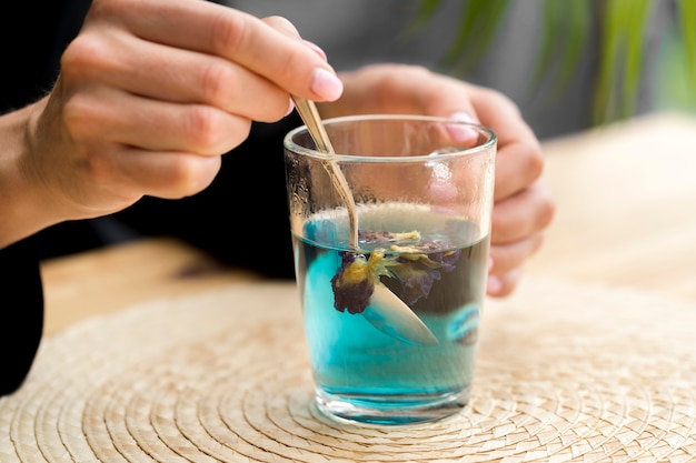 Free photo woman stirring blue tea in glass