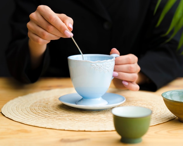 ティースプーンでマグカップでお茶をかき混ぜる女性