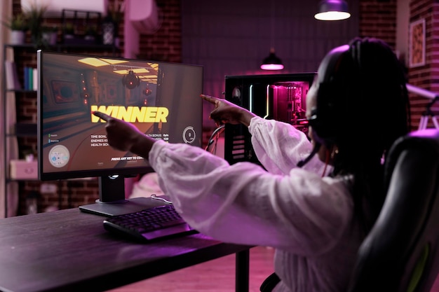 여자 스트리머는 컴퓨터에서 비디오 게임 토너먼트를 하고 승리를 축하합니다. 여성 플레이어가 액션 게임 챔피언십에서 우승하고 PC에서 온라인 게임 플레이 경쟁을 즐깁니다.