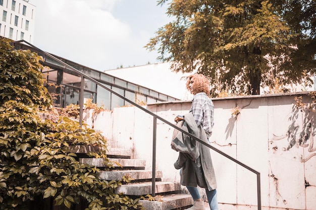 Free photo woman in street wear standing on steps