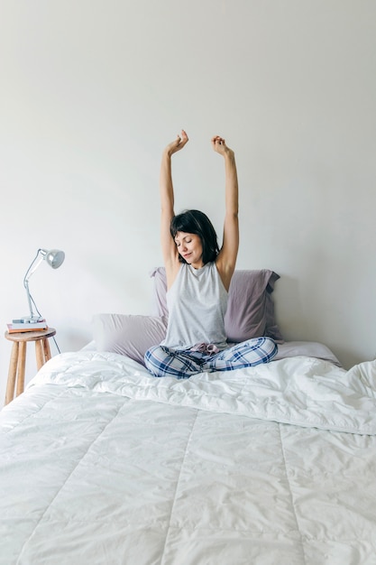 Woman stretching arms on bed