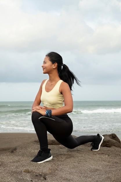 Woman stretching at beach full shot