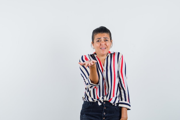 woman stretching hand in puzzled gesture in shirt, skirt