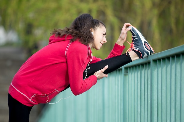 Free photo woman stretching her leg on a handrail