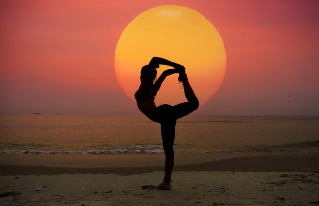 Woman stretching leg by the back on the beach