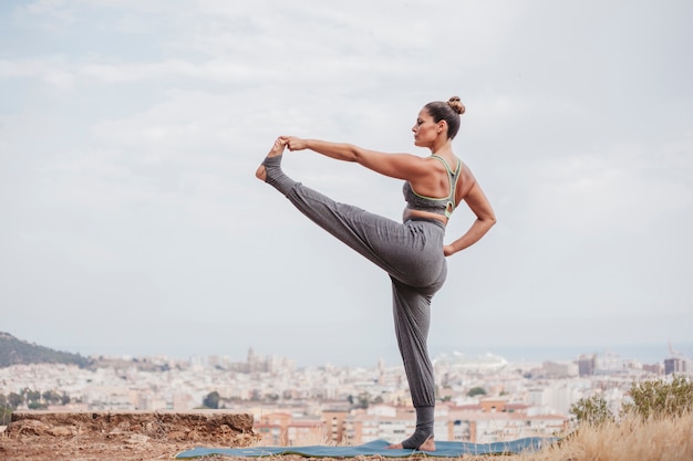 Free photo woman stretching leg in front of city