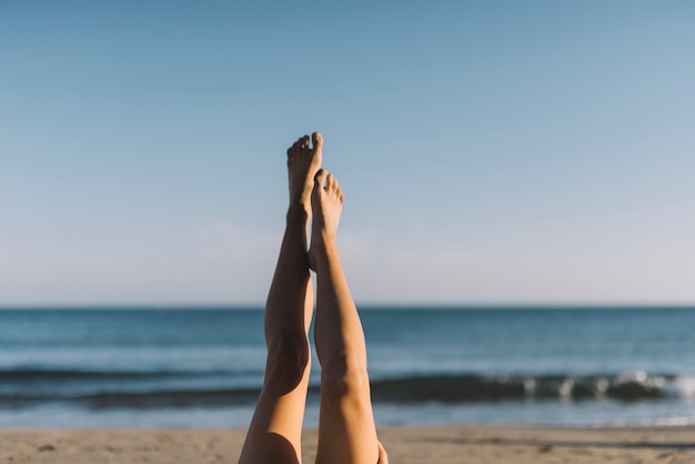 ビーチで横たわっている脚を伸ばしている女性