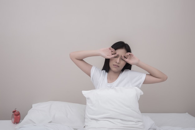 Woman stretching with closed eyes sitting on bed