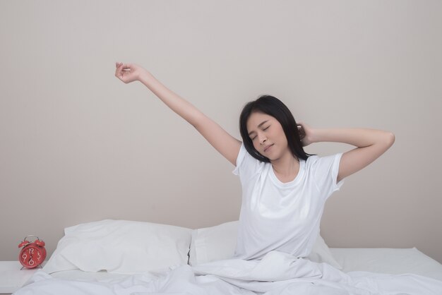 Woman stretching with closed eyes sitting on bed