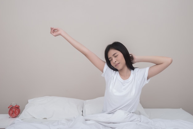 Woman stretching with closed eyes sitting on bed