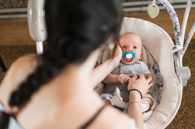 Woman stroking her baby lying on baby carriage