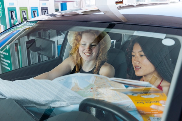 Woman studying road map sitting in car