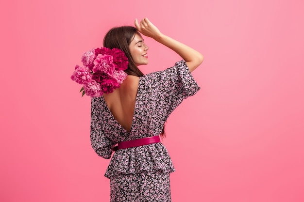 Stile di donna in abito con fiori su sfondo rosa