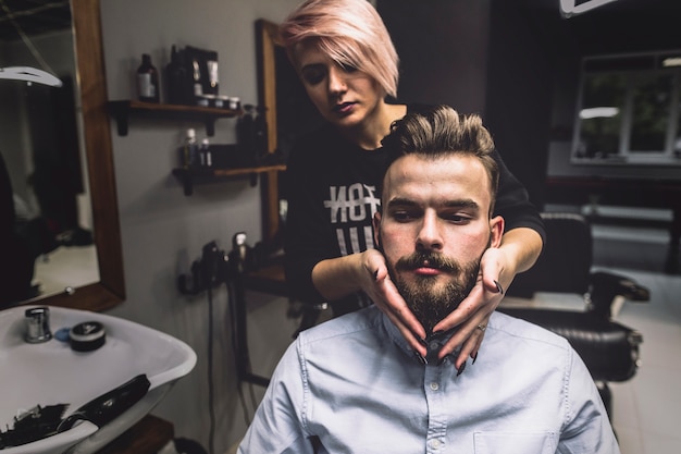 Woman styling beard of customer