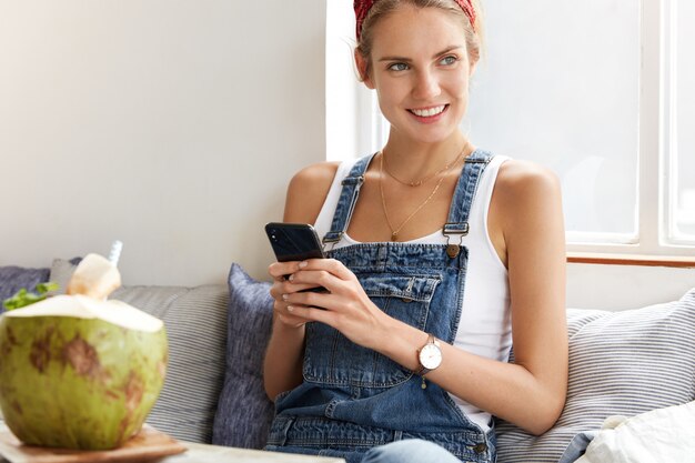 コーヒーショップでスタイリッシュなデニムのオーバーオールの女性