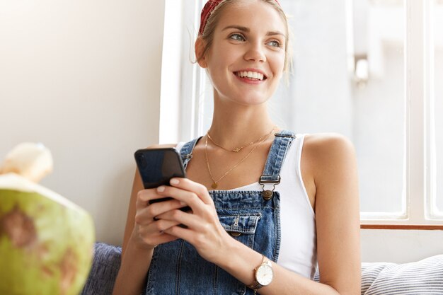 コーヒーショップでスタイリッシュなデニムのオーバーオールの女性