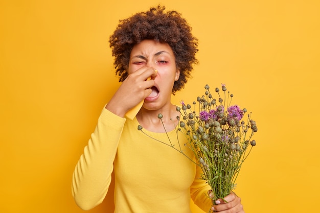 woman suffers from allergic rhinitis uses napkin to blow nose needs effective medicine to cure disease has allergy on wildflowers isolated on yellow 