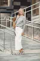 Free photo woman in a summer city. lady with brown bags. woman in a gray sweater.