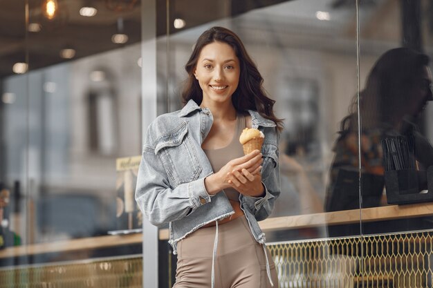 夏の街の女性。アイスクリームの女性。建物のそばのブルネット。