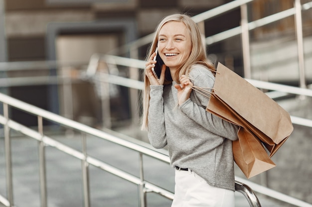 Woman in a summer city. lady with mobile phone. woman in a gray sweater.