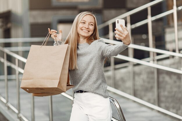 Woman in a summer city. Lady with mobile phone. Woman in a gray sweater.