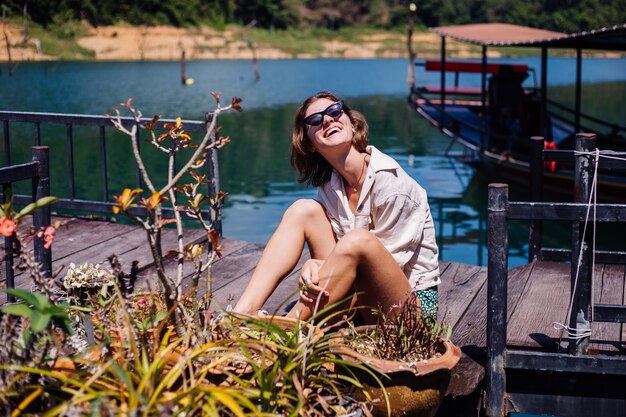 Woman in summer dress and jacket tourist travel in Thailand, Khao Sok national park, amazing view on boats and lake.