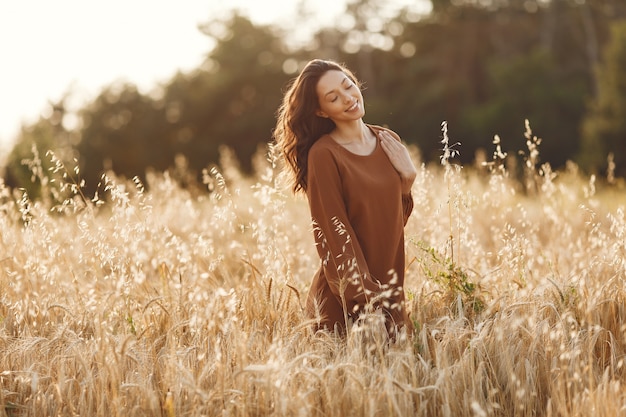 Woman in a summer field. Brunette in a brown sweater. 