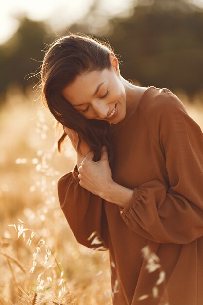 Woman in a summer field. Brunette in a brown sweater.