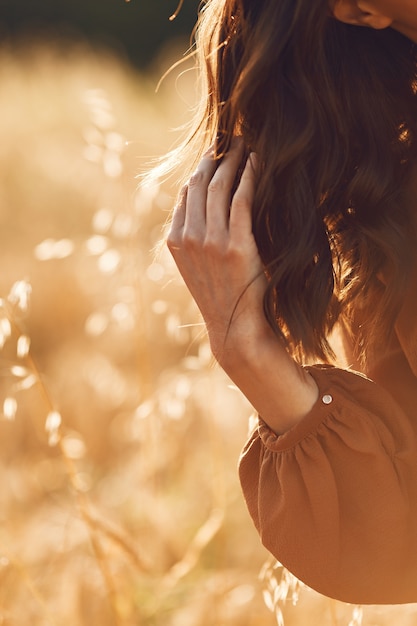 Woman in a summer field. Brunette in a brown sweater. 