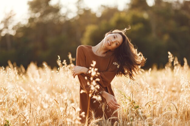 夏の畑の女性。茶色のセーターを着たブルネット。