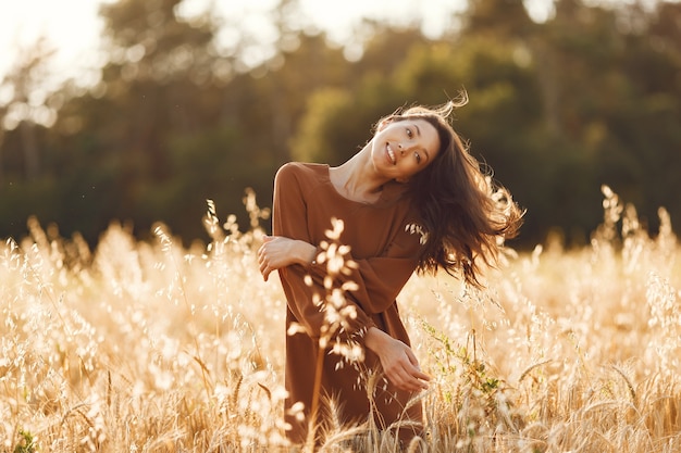 Woman in a summer field. Brunette in a brown sweater. 