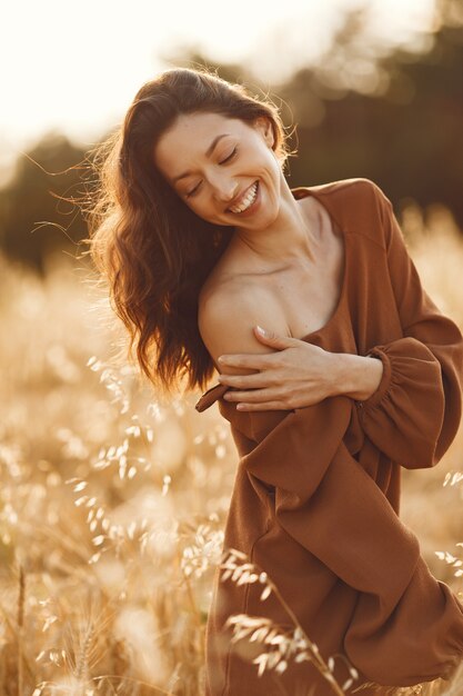 Woman in a summer field. Brunette in a brown sweater. 