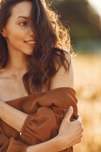 Woman in a summer field. Brunette in a brown sweater. 