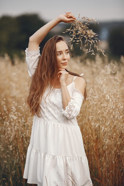 夏の畑の女性。白いドレスのブルネット。