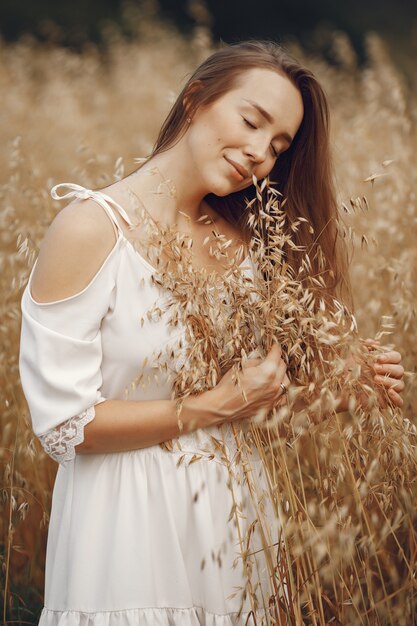 Woman in a summer field. Brunette in a white dress. 