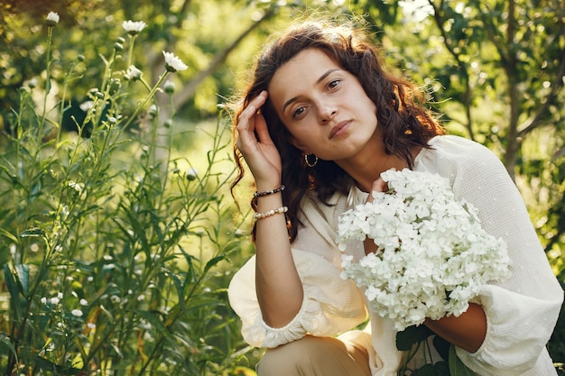 Woman in a summer field. Brunette in a white shirt.