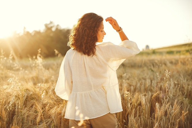 Woman in a summer field. Brunette in a white shirt.