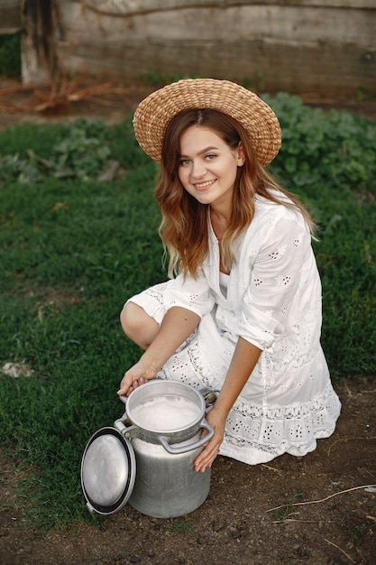 Free photo woman in a summer field. girl in a white dress. woman with barrel of milk.